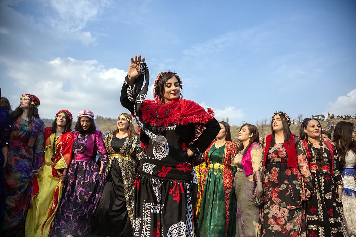 Rengârenk geleneksel kirasfistanlar giymiş Kürt kadınları Newroz kutlamasında el ele halay çekiyor