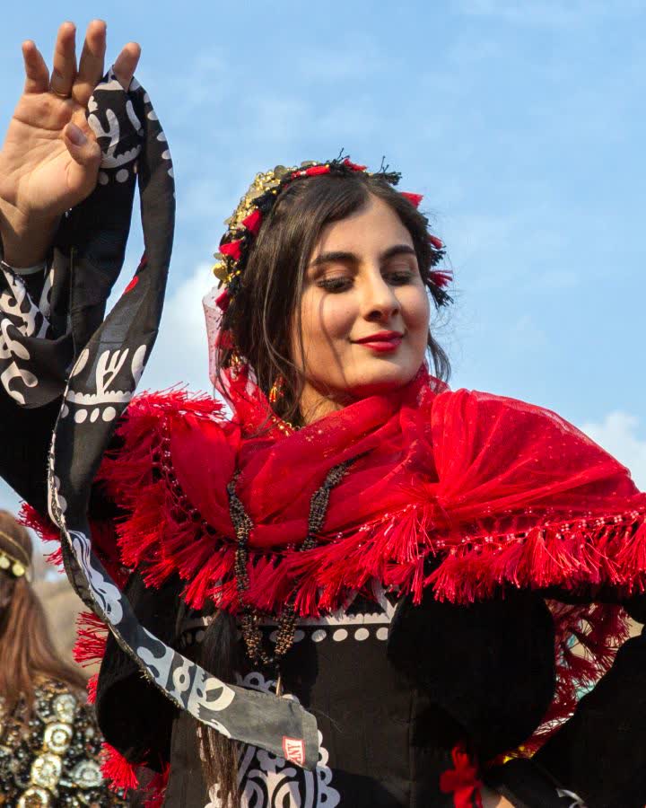 Kırmızı püsküllü şal ve siyah işlemeli elbiseyle dans eden kadın