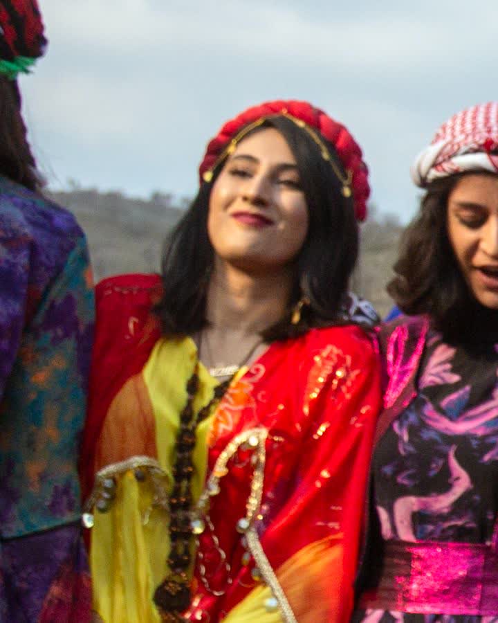 Sarı ve kırmızı tonlarda geleneksel elbiseli kadınlar halayda
