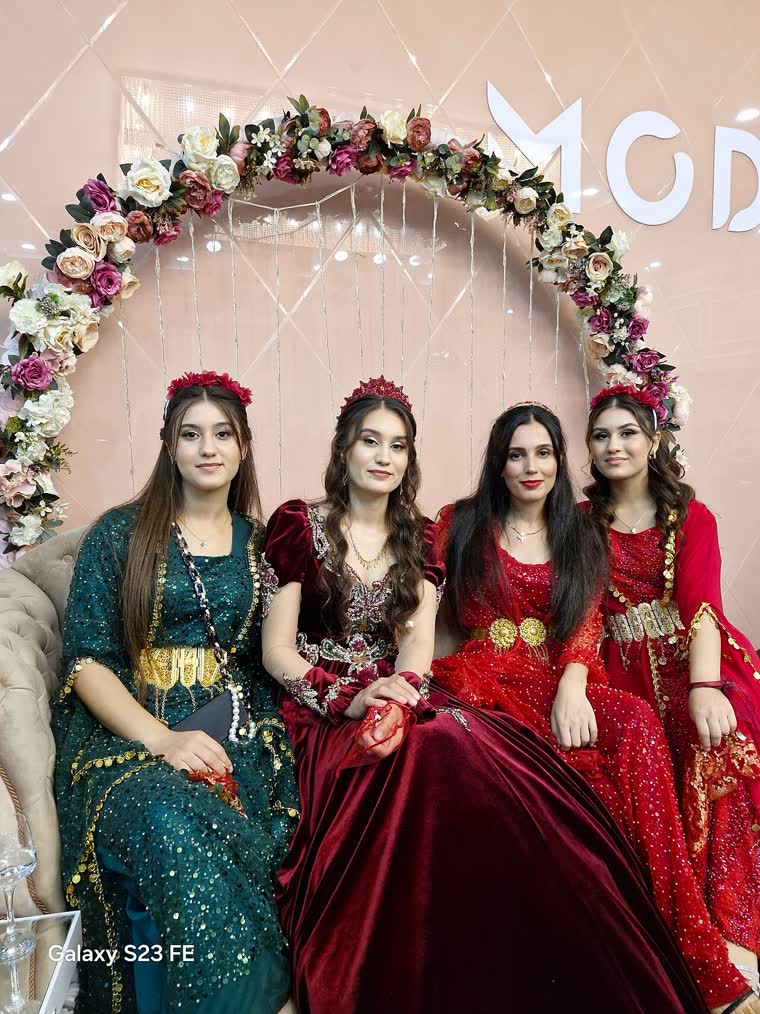 Zümrüt ve bordo kadife kirasfistanlar, altın kofi ve takılarla çiçek dekorlu salonda dört genç kadın