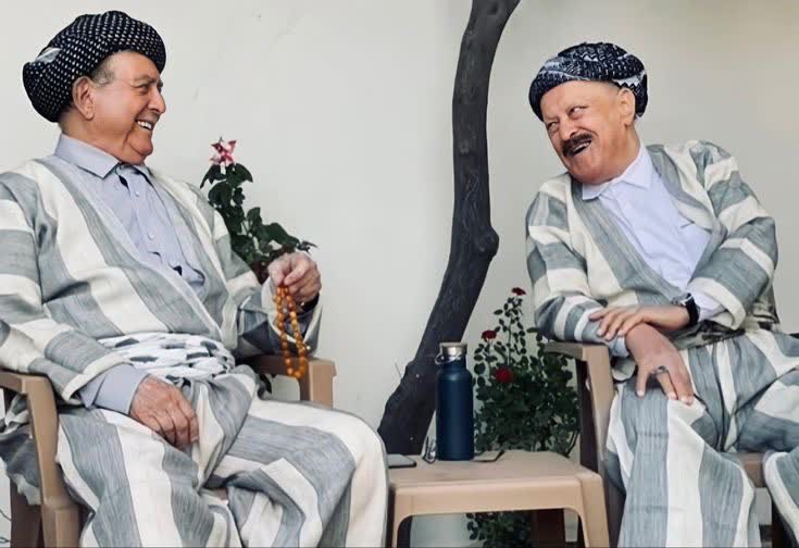Gri çizgili şal û şepik takımları ve puşi sarıklarıyla sohbet eden iki yaşlı beyefendi